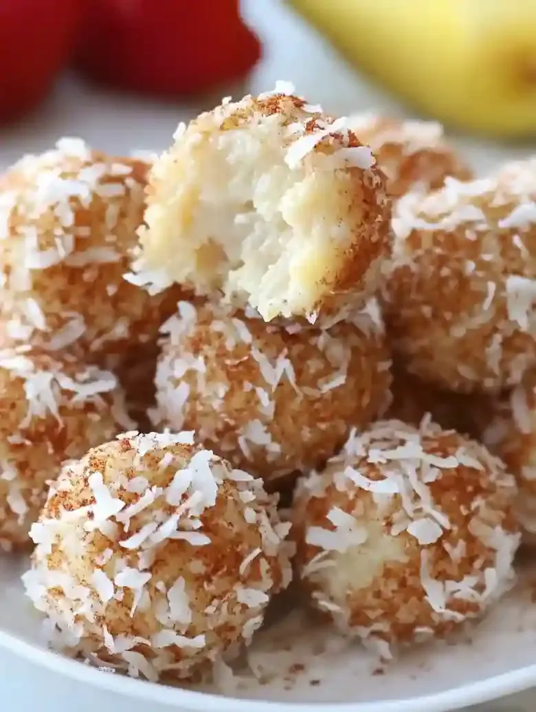 Dessert balls coated in coconut with bites revealing chicken tender filling.