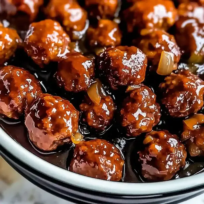 Savory meatballs in golden sauce on a white marble surface.